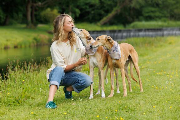 woman with two dogs in a grassy area beside a river