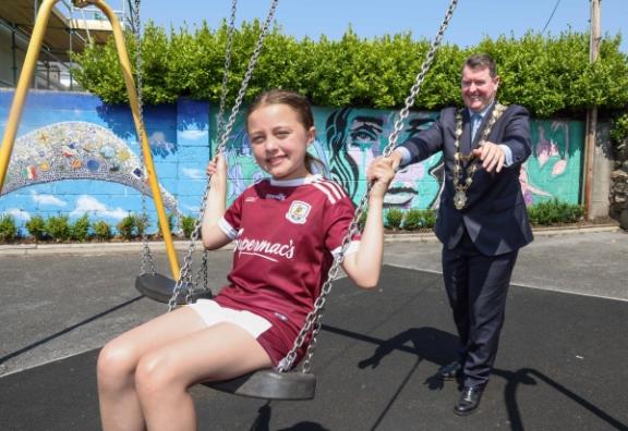 Mayor Keane pushing Mary Byrne's grand neice on the swings at the newly namedHenry St Playground