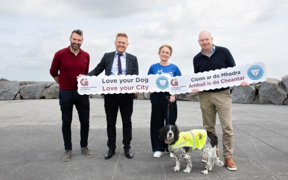 Officials posing for picture with signs and a dog