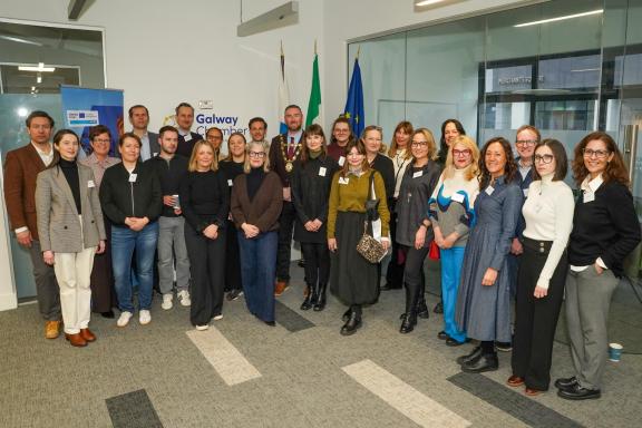Delegations posing for photo together in office room.