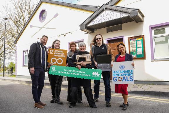 People standing outside the Rowing Club holding sustainable goalds boards.