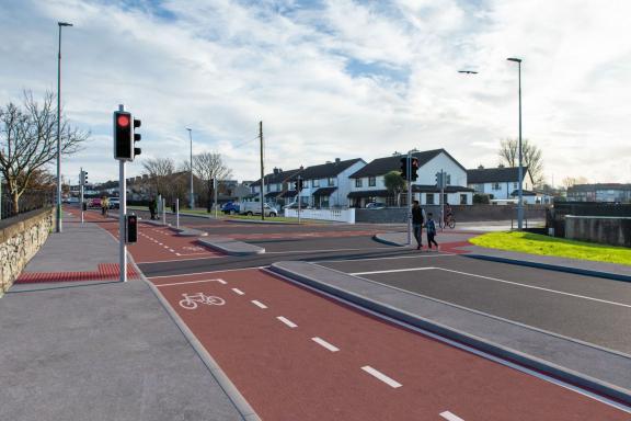 A photomontage image showing part of the future Monivea Road (East) Active Travel Scheme.  This image shows the proposed works, including the new cycle lane and people crossing at traffic lights.