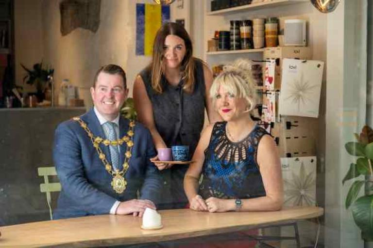 Mayor with owner of Fairhill Cafe and performer Tracy Bruen sitting in the window of Fairhill cafe