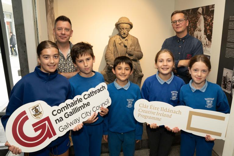 People standing with Padraic O Conaire statue in museum.
