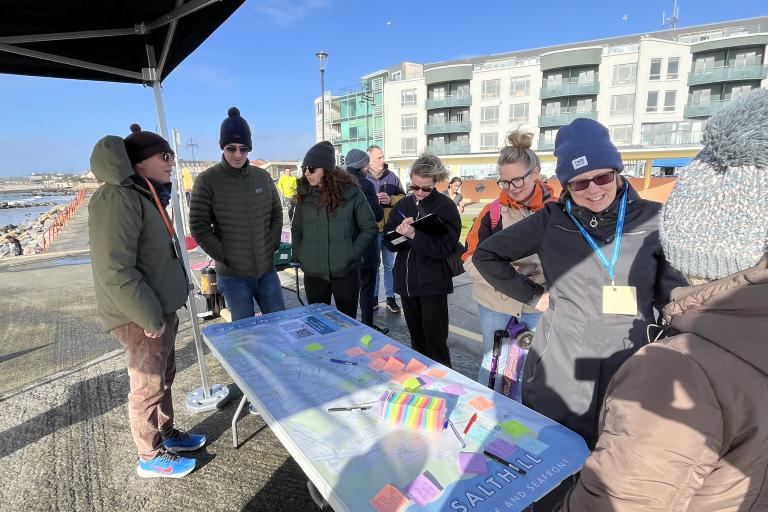 Salthill Public Consultation on Prom with people standing at table of post its with ideas written on them. 