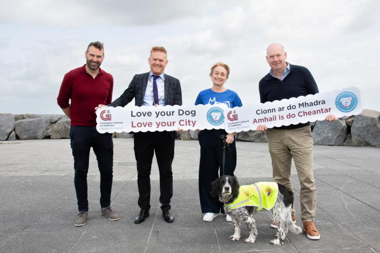 Officials posing for picture with signs and a dog