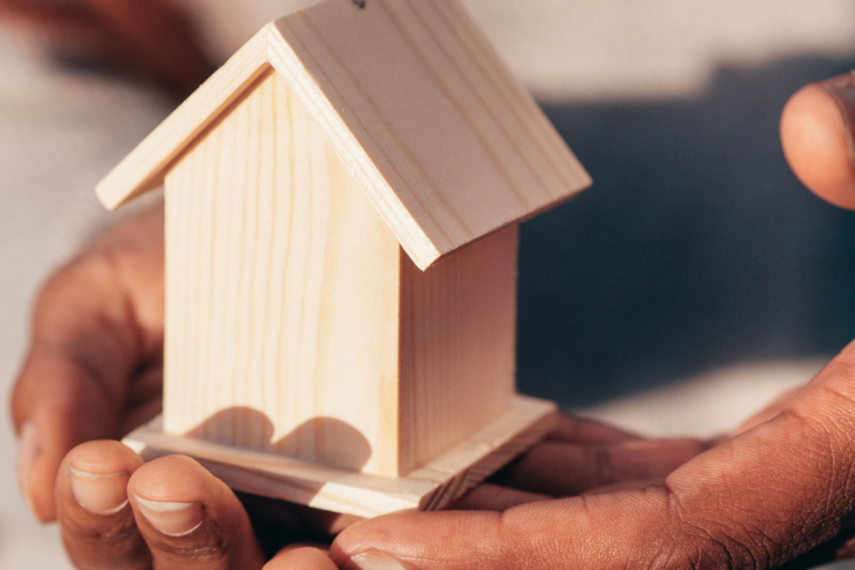 stock image of hands holding a small wooden house