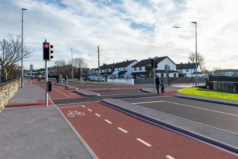 A photomontage image showing part of the future Monivea Road (East) Active Travel Scheme.  This image shows the proposed works, including the new cycle lane and people crossing at traffic lights.
