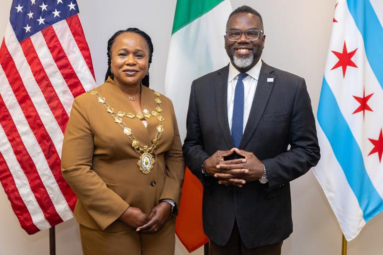 Two mayors standing in front of the american and Irish flags