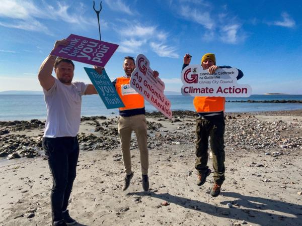 People jumping on a beach holding signs for Clean Coasts and GCC Climate Action