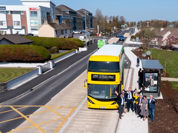 A drone shot of a group of people in front of a bus, at the opening of the project.