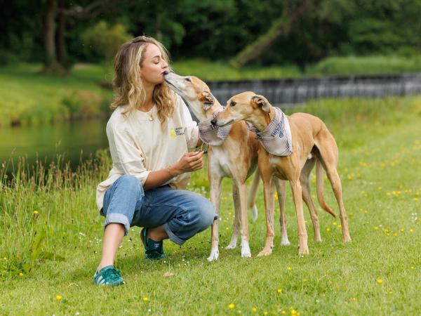 woman with two dogs in a grassy area beside a river