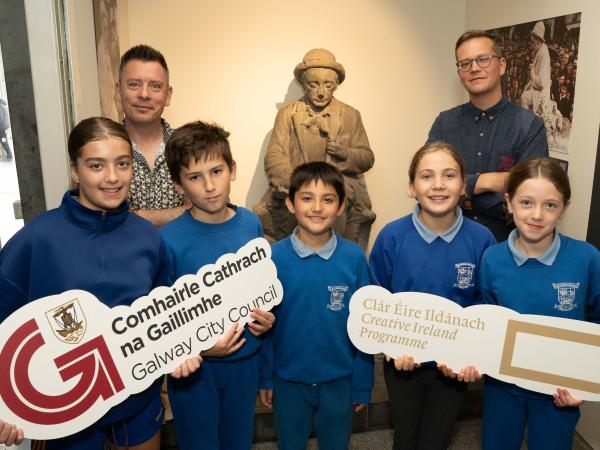 People standing with Padraic O Conaire statue in museum.
