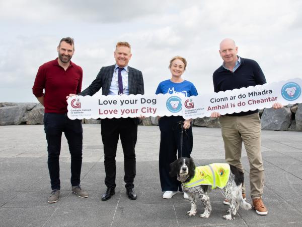 Officials posing for picture with signs and a dog