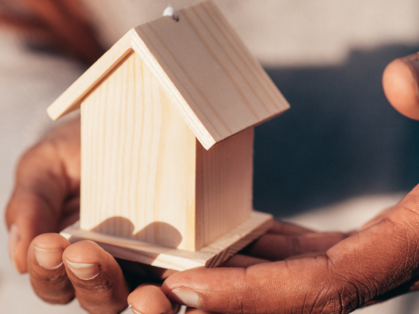 stock image of hands holding a small wooden house