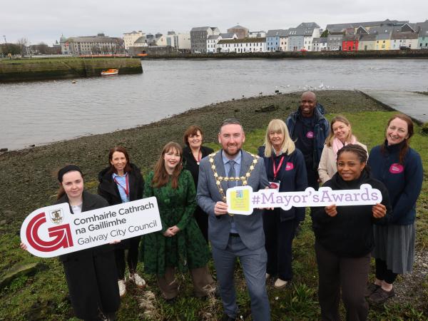 GCC Staff and Mayor standing at the Claddagh Basin holding up the Galway City Council Logo. The long walk is behind them.