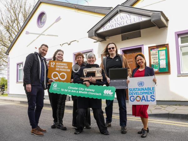 People standing outside the Rowing Club holding sustainable goalds boards.