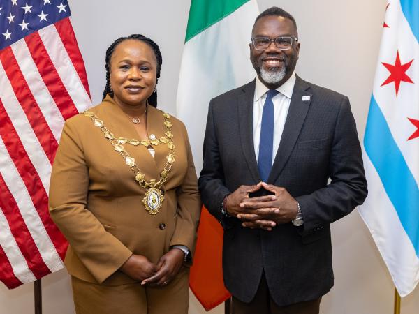 Two mayors standing in front of the american and Irish flags