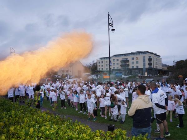 People lined up and dancing at Colour Run, flare of orange paint
