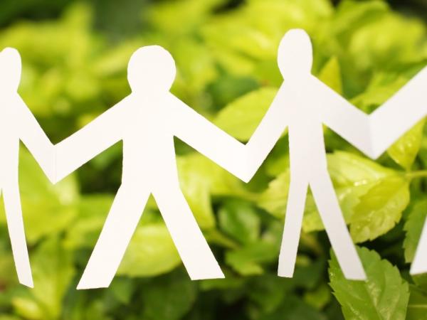 Paper men holding hands in front of greenery